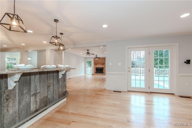 kitchen with light wood-type flooring, a brick fireplace, open floor plan, and decorative light fixtures