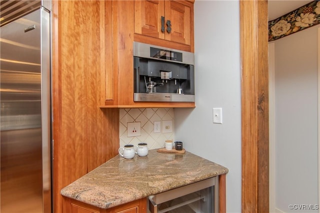 kitchen with light stone counters, high end fridge, beverage cooler, and brown cabinets