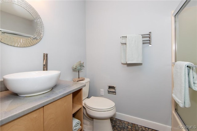 bathroom featuring baseboards, vanity, toilet, and combined bath / shower with glass door