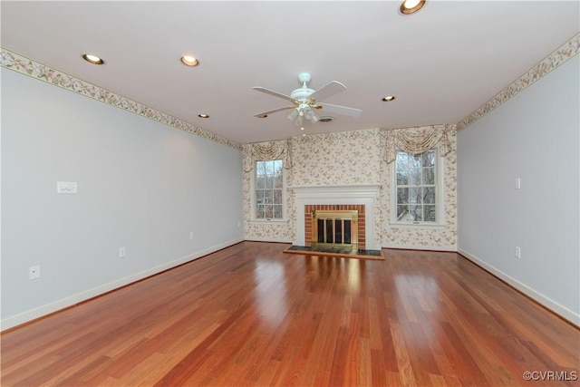 unfurnished living room with a brick fireplace, baseboards, and wood finished floors