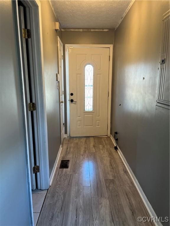 doorway with a textured ceiling and hardwood / wood-style flooring