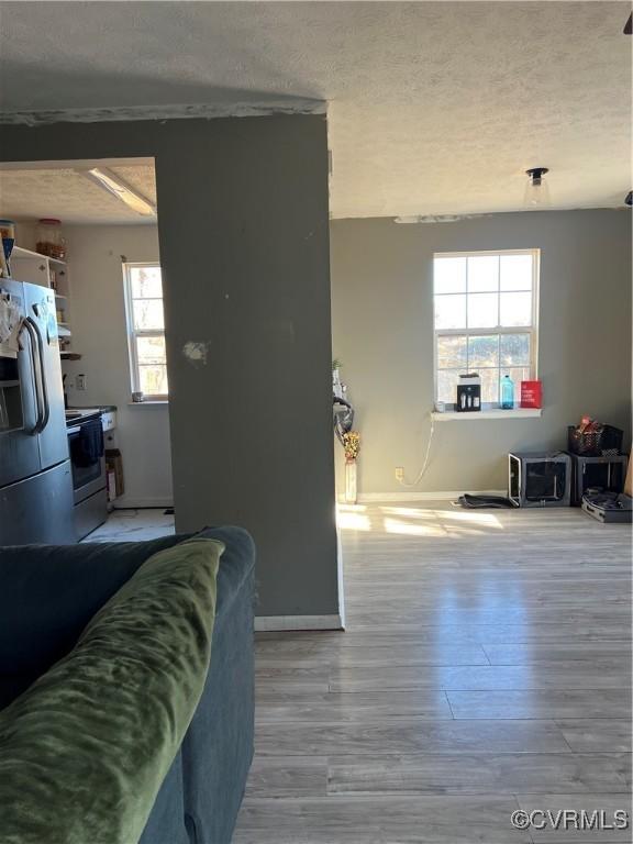 interior space with a textured ceiling, a healthy amount of sunlight, white appliances, and light hardwood / wood-style floors