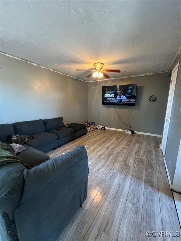 living room with ceiling fan, wood-type flooring, and a textured ceiling