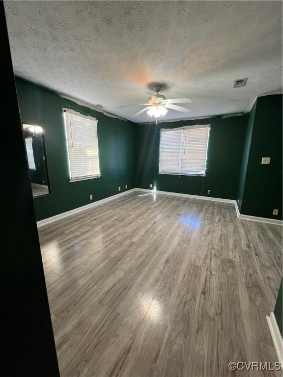 spare room with ceiling fan, wood-type flooring, and a textured ceiling