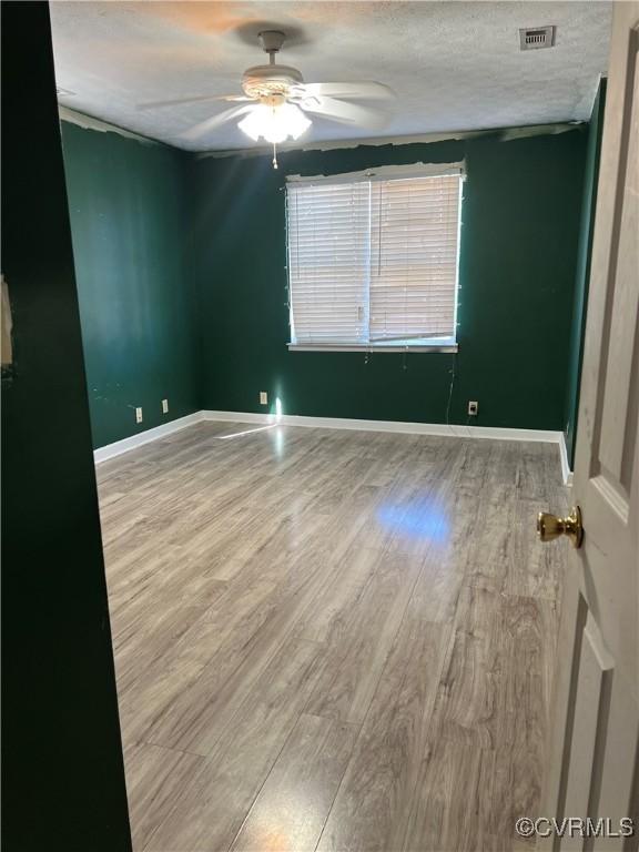 unfurnished room with hardwood / wood-style floors, ceiling fan, and a textured ceiling