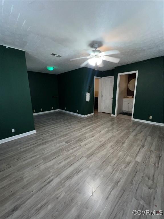 interior space with ceiling fan, wood-type flooring, and a textured ceiling