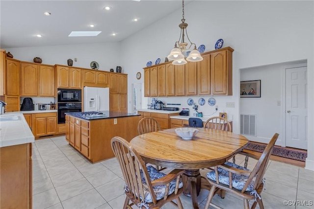 kitchen with pendant lighting, a center island, black appliances, a skylight, and a chandelier