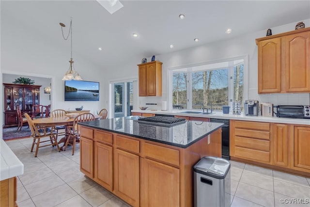 kitchen featuring a center island, vaulted ceiling, light tile patterned floors, pendant lighting, and black dishwasher