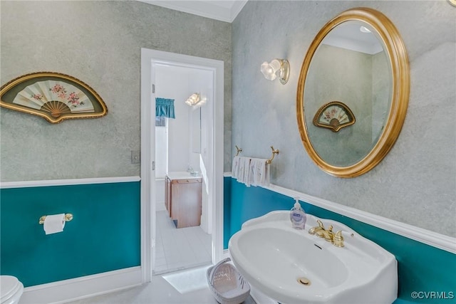 bathroom with toilet, crown molding, and sink