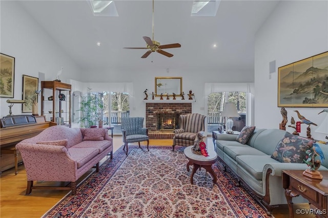 living room with hardwood / wood-style floors, a skylight, a brick fireplace, and a healthy amount of sunlight