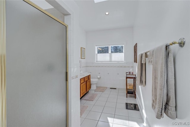 bathroom with walk in shower, vanity, tile walls, tile patterned flooring, and toilet