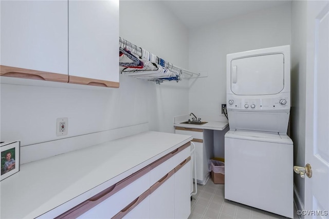 laundry area with stacked washer / drying machine and cabinets