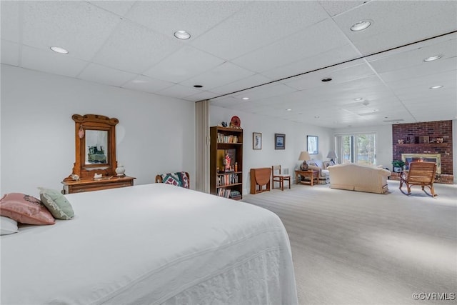 bedroom with carpet, a brick fireplace, and a drop ceiling