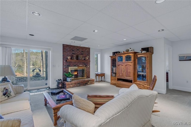 carpeted living room with a fireplace, a healthy amount of sunlight, and a drop ceiling