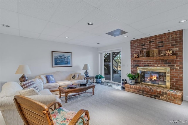 living room with a drop ceiling, carpet floors, and a fireplace