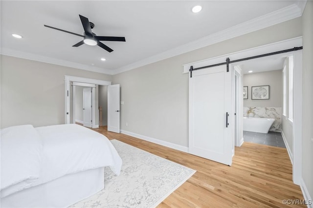 bedroom with hardwood / wood-style flooring, ceiling fan, ensuite bathroom, ornamental molding, and a barn door