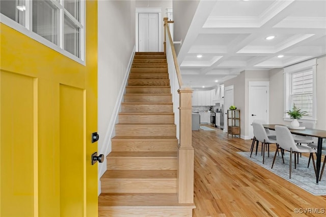 staircase with ornamental molding, coffered ceiling, hardwood / wood-style floors, and beam ceiling