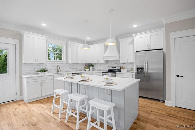 kitchen featuring sink, white cabinetry, decorative light fixtures, appliances with stainless steel finishes, and a kitchen island