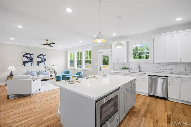 kitchen with decorative light fixtures, tasteful backsplash, sink, white cabinets, and stainless steel appliances