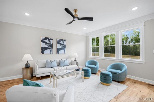 living room featuring crown molding, light hardwood / wood-style floors, and ceiling fan