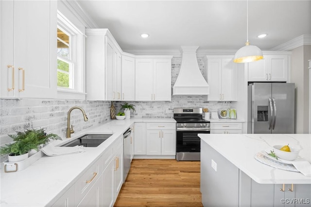 kitchen with premium range hood, appliances with stainless steel finishes, pendant lighting, white cabinetry, and sink