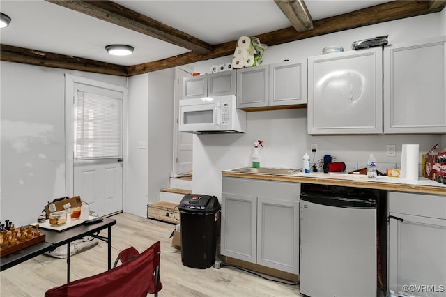 kitchen with beamed ceiling, light wood-type flooring, stainless steel refrigerator, and gray cabinetry