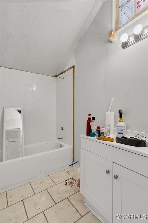 bathroom featuring tiled shower / bath combo, lofted ceiling, and vanity