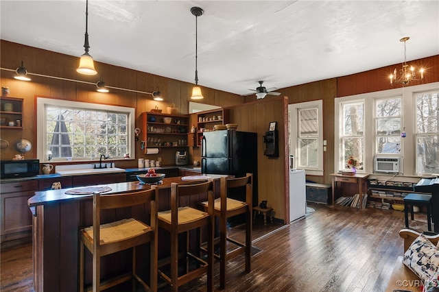 bar featuring pendant lighting, dark hardwood / wood-style flooring, black appliances, and ceiling fan with notable chandelier