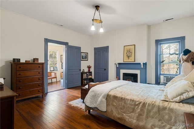 bedroom featuring multiple windows, dark hardwood / wood-style flooring, and cooling unit