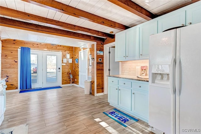 kitchen featuring light hardwood / wood-style floors, wood walls, white fridge with ice dispenser, and beam ceiling