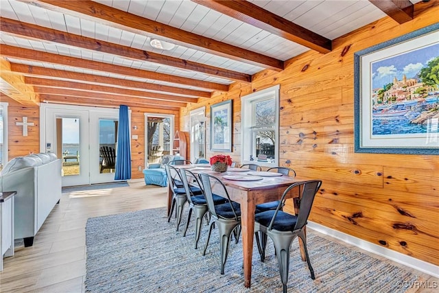 dining room featuring beamed ceiling, light hardwood / wood-style flooring, wooden walls, and wood ceiling