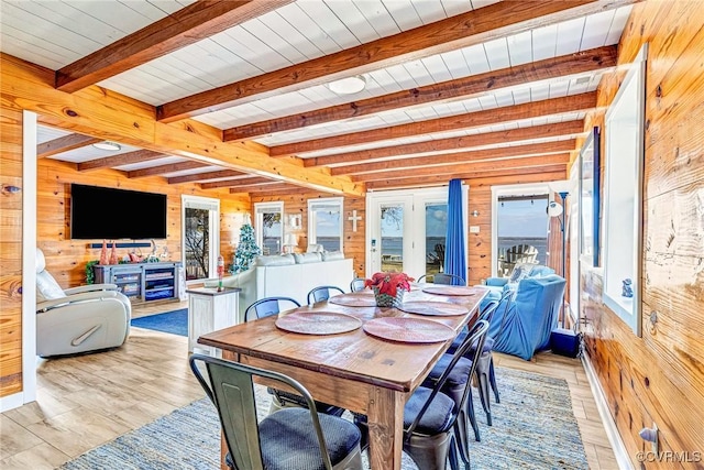 dining area featuring beam ceiling, light wood-type flooring, wood ceiling, and wood walls