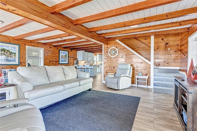 living room with beam ceiling, light hardwood / wood-style floors, wood ceiling, and wood walls