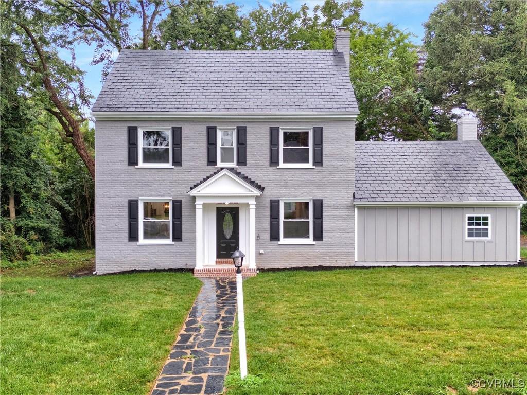 colonial-style house featuring a front yard