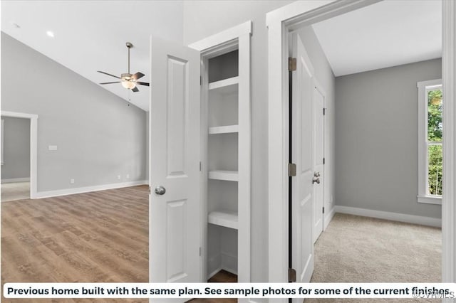 hallway with light wood-type flooring, lofted ceiling, and built in shelves