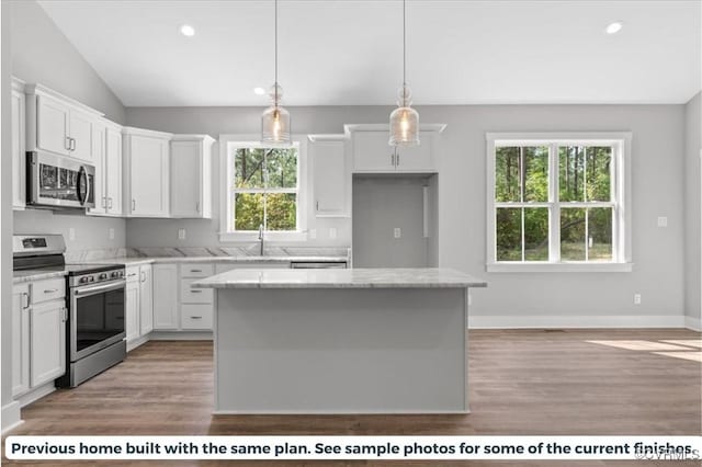 kitchen featuring appliances with stainless steel finishes, white cabinetry, a center island, and decorative light fixtures