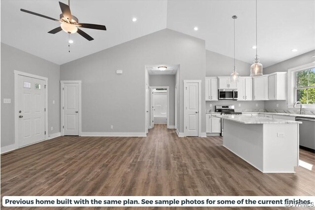 kitchen featuring a kitchen island, stainless steel appliances, decorative light fixtures, and white cabinets