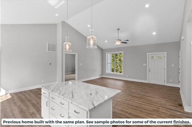 kitchen with hanging light fixtures, ceiling fan, dark wood-type flooring, a kitchen island, and white cabinets