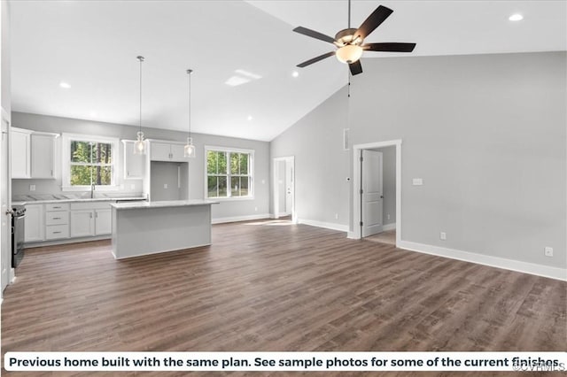 kitchen featuring ceiling fan, dark wood-type flooring, high vaulted ceiling, a kitchen island, and white cabinetry