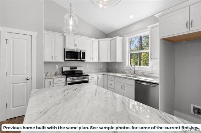 kitchen featuring white cabinets, appliances with stainless steel finishes, light stone countertops, and sink