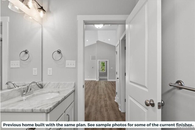 bathroom with lofted ceiling, vanity, and hardwood / wood-style floors