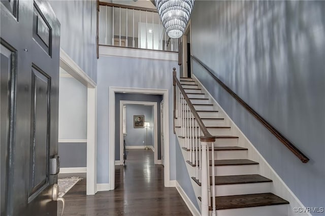 foyer with a high ceiling, an inviting chandelier, and dark wood-type flooring