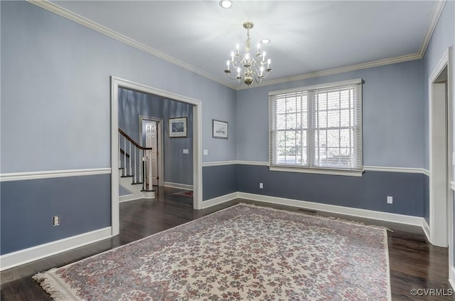 spare room featuring a chandelier, crown molding, and dark wood-type flooring