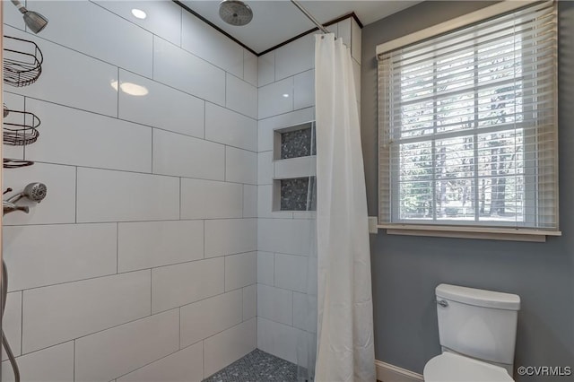 bathroom featuring walk in shower, toilet, and plenty of natural light