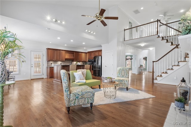 living area with ceiling fan, wood finished floors, visible vents, stairs, and crown molding