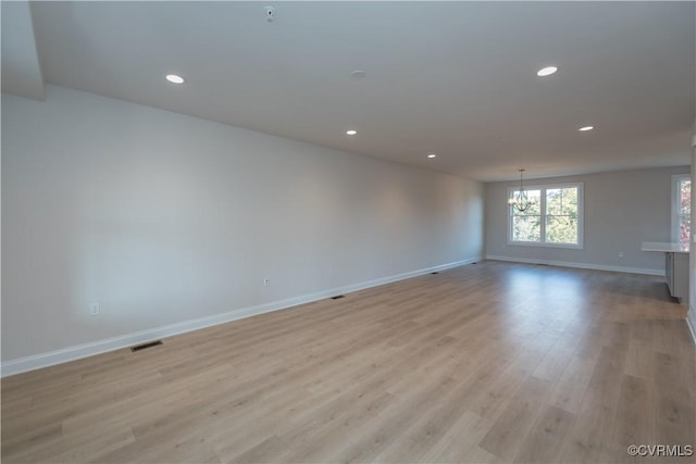 spare room with light wood-type flooring and an inviting chandelier