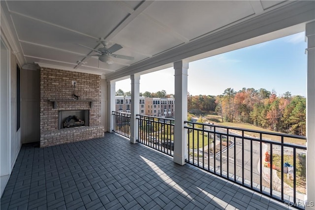 view of patio / terrace with ceiling fan, a balcony, and an outdoor brick fireplace