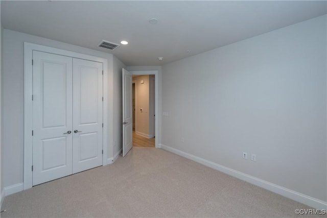 unfurnished bedroom featuring a closet and light colored carpet