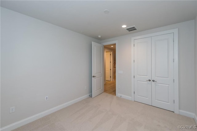 unfurnished bedroom with light carpet and a closet