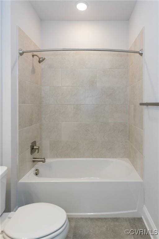 bathroom with tile patterned flooring, tiled shower / bath combo, and toilet